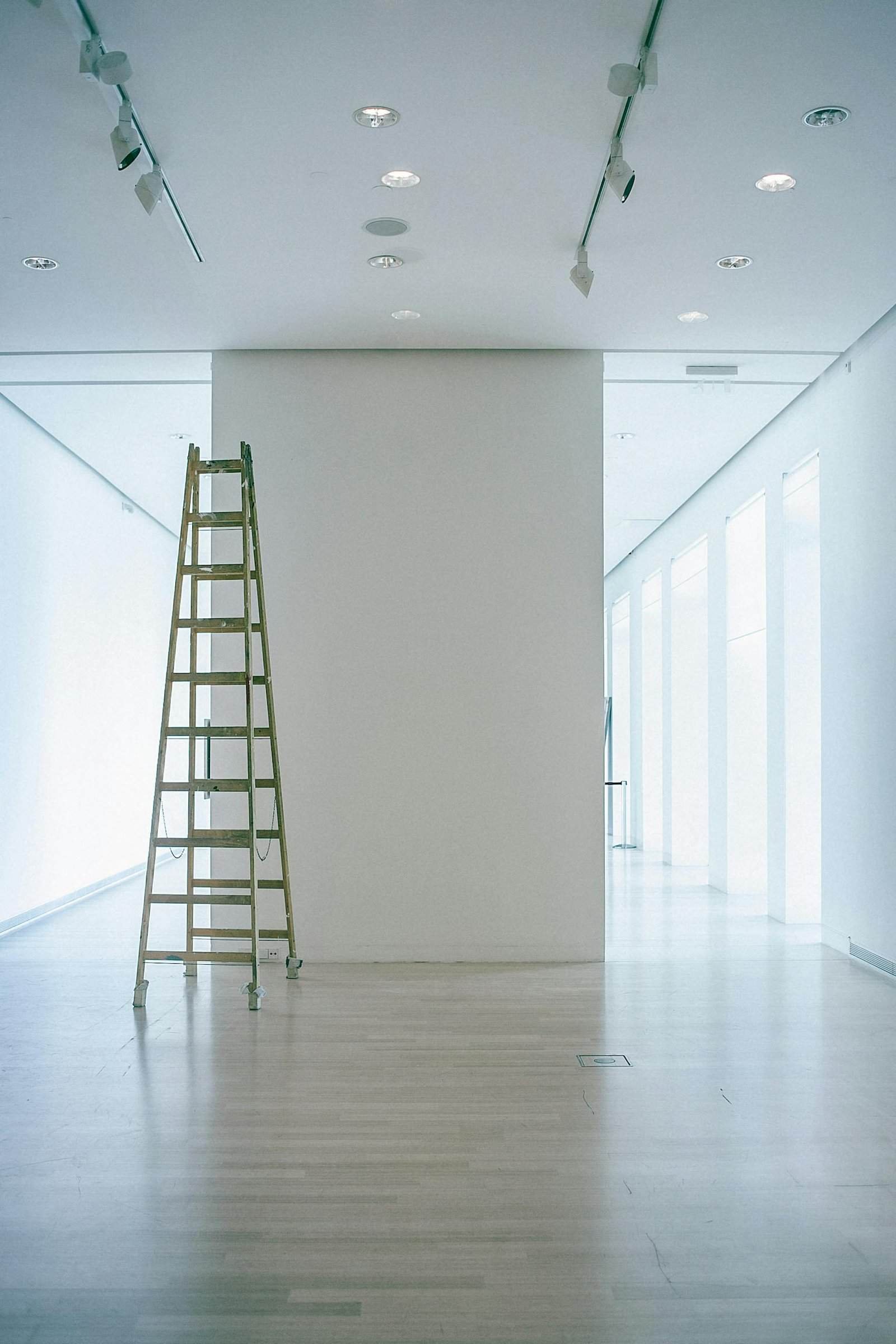 Wide indoor space with a ladder, showcasing LED lighting and modern minimalism.